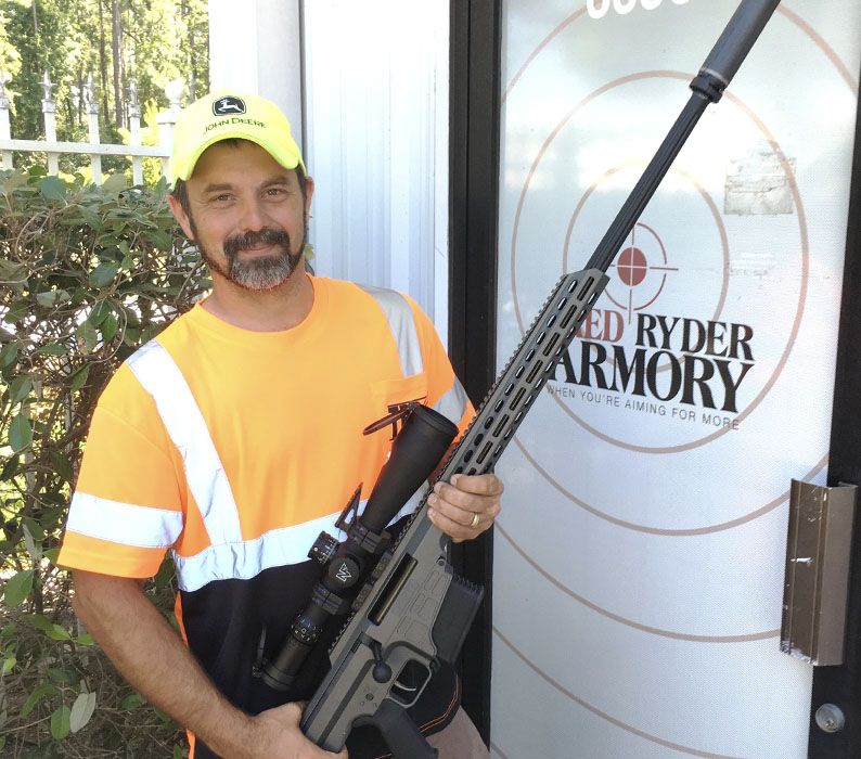 Customer holding Barrett MRAD .338 Lapua rifle with Night Force ATACR 7-35x56 optic and Silencerco Hybrid 46 Suppressor sold at Red Ryder Armory in Jacksonville FL